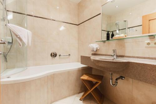 a bathroom with a sink and a bath tub and a sink at Alpinhotel Berghaus spa in Tux