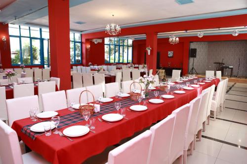 długi stół w pokoju z czerwonymi ścianami i białymi krzesłami w obiekcie Hotel Grand w mieście Nizhnyaya Alekseyevka