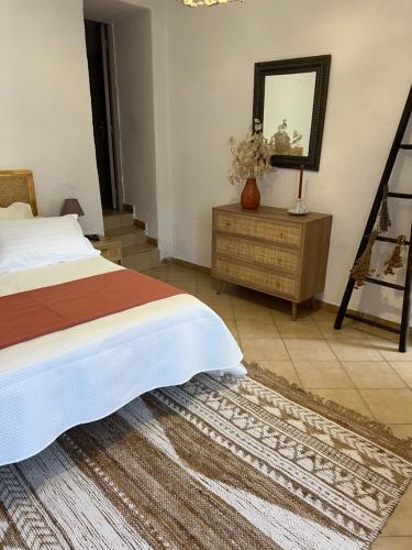 une chambre avec un lit, une commode et un miroir dans l'établissement Maison de village, à Manso