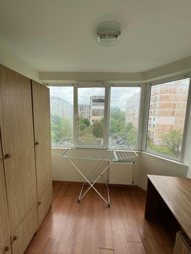 ein Zimmer mit großen Fenstern, einem Tisch und einem Stuhl in der Unterkunft Sun Apartment in Chişinău