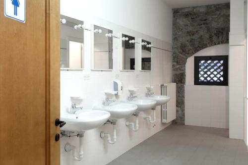 a bathroom with four sinks and a row of mirrors at Ostello IMPERINA in Zenich