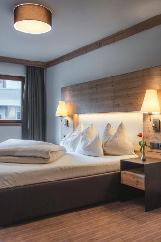 a bedroom with a large bed with a wooden headboard at Alpinhotel Berghaus spa in Tux