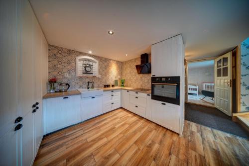 a large kitchen with white cabinets and a wooden floor at Chaloupka u potoka in Kutná Hora
