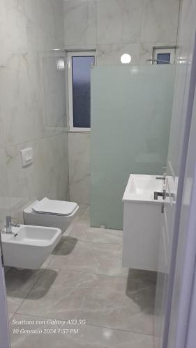 een witte badkamer met een toilet en een wastafel bij Casa Sarà in Pogradec