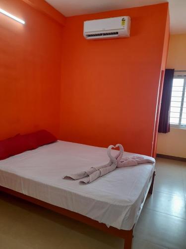 a bedroom with a bed with an orange wall at Aryas Residency in Coimbatore
