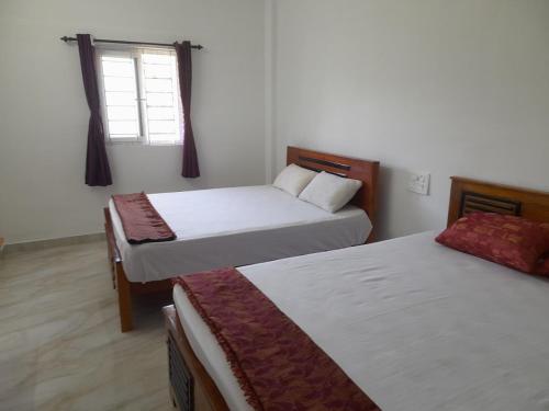 a bedroom with two beds and a window at Aryas Residency in Coimbatore