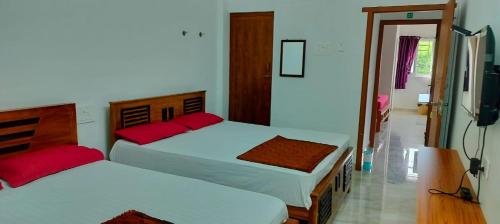 two beds with red pillows in a room at Aryas Residency in Coimbatore