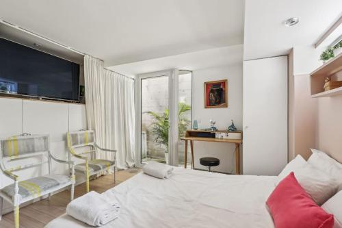 une chambre avec un grand lit blanc et un bureau dans l'établissement Maison d'architecte Sacré Coeur, à Paris