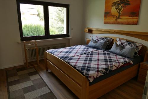 a bedroom with a bed with a plaid blanket and a window at Ferienwohnung Hilberath in Wimbach