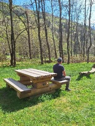 a man sitting on a bench next to a picnic table at Acero Rosso in Malonno