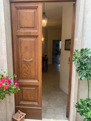 a wooden door leading into a hallway with flowers at Dimora Scarnabecco in Todi