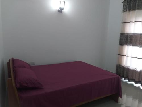 Dormitorio con cama morada con cortinas y lámpara en Ariyana resort, en Athurugiriya