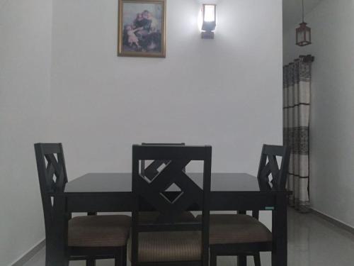 mesa de comedor con 2 sillas y una foto en la pared en Ariyana resort, en Athurugiriya