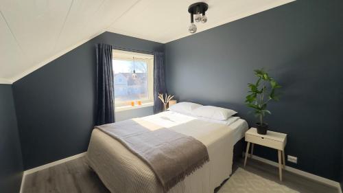 Un dormitorio con una cama con paredes azules y una ventana en House with perfect location in Leknes en Leknes