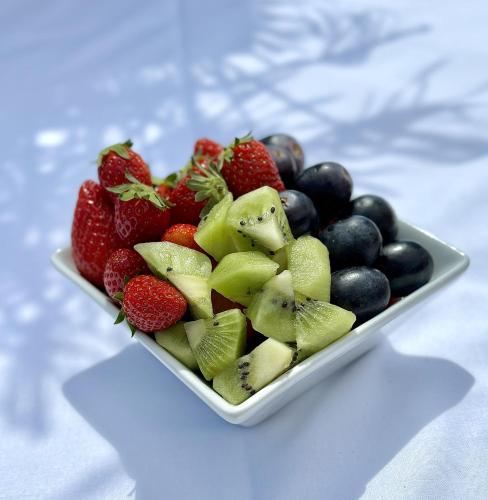 a plate of strawberries and kiwis and other fruit at Residence Canella in Sari Solenzara