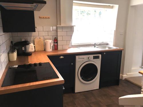 eine Küche mit einer Waschmaschine und einem Waschbecken in der Unterkunft The Burrow in Wetherby