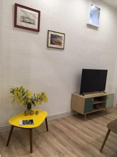 un salon avec une télévision et une table dans l'établissement Le chant des vagues, à Sète