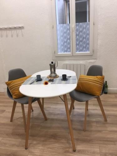 une table blanche et deux chaises dans une pièce dans l'établissement Le chant des vagues, à Sète