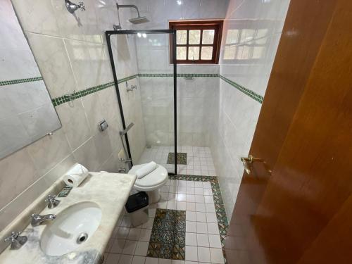 a bathroom with a shower and a sink and a toilet at Pousada Atalaia Capivari in Campos do Jordão