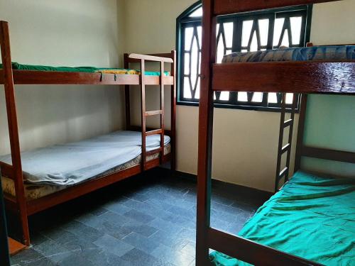 a room with three bunk beds and a window at Hospedagem Familiar in Piúma