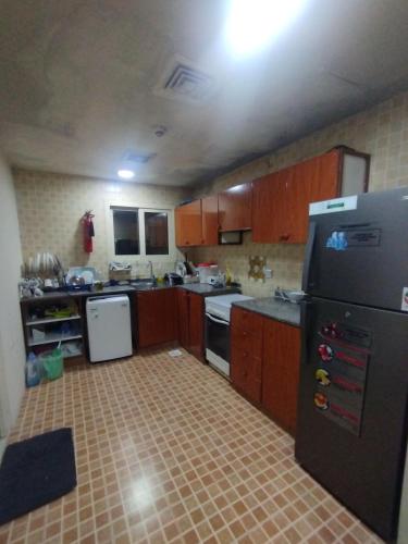 a small kitchen with a black refrigerator and cabinets at Fully furnished room in Sharjah
