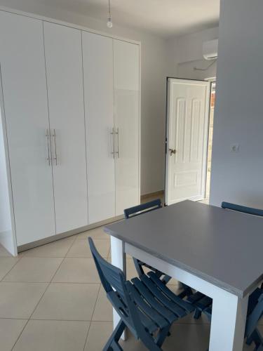 a kitchen with white cabinets and a table and chairs at Qeparo Andrea Markou rooms in Qeparo