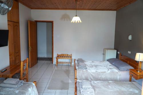 a room with three beds and a table and a chair at Hotel Defkalion in Álli Meriá