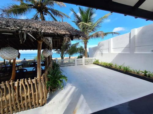 a walkway leading to a resort with palm trees and the ocean at Sailors' Bay in Hikkaduwa