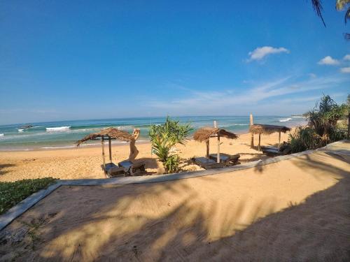 a beach with umbrellas and chairs and the ocean at Sailors' Bay in Hikkaduwa
