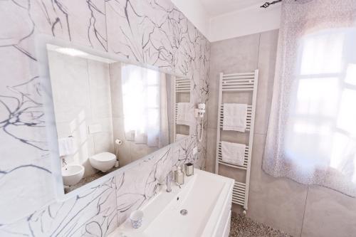 a white bathroom with a sink and a mirror at Villa Mandrioli in Cecina