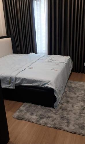 a bed in a bedroom with a rug and a window at Căn hộ 2 Phòng Ngủ Vinhomes Grand Park, Thủ Đức city, Hồ Chí Minh city in Gò Công