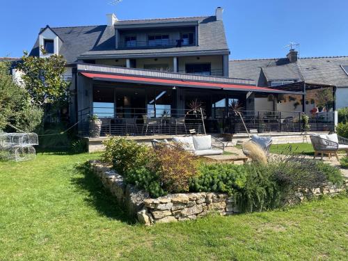 duży dom z kamienną ścianą na dziedzińcu w obiekcie La Bellevue Bistrot et Chambres d'Hotes w mieście Séné