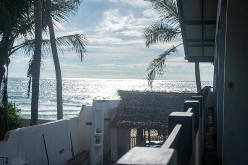 a view of the ocean from a beach with palm trees at Sailors' Bay in Hikkaduwa