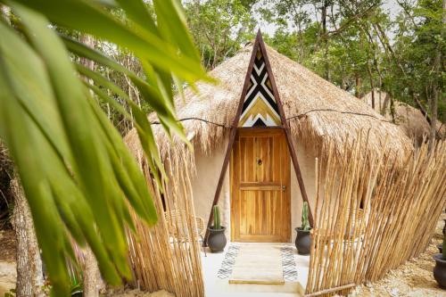 een hut met rieten dak en een houten deur bij The Yellow Nest Tulum in Tulum