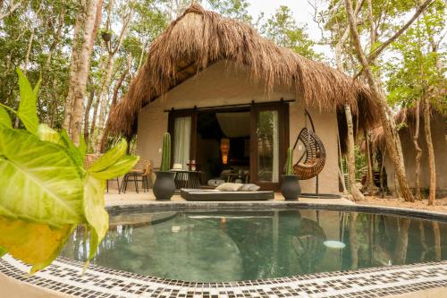 a small hut with a swimming pool in front of it at The Yellow Nest Tulum in Tulum