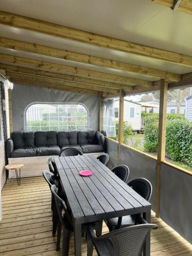 une table et des chaises sur une terrasse avec un canapé dans l'établissement Mobil-home neuf 8 personnes, à Gastes