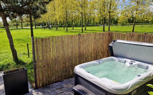 a hot tub in a backyard with a fence at Chalet de Scherpenweide in Leur