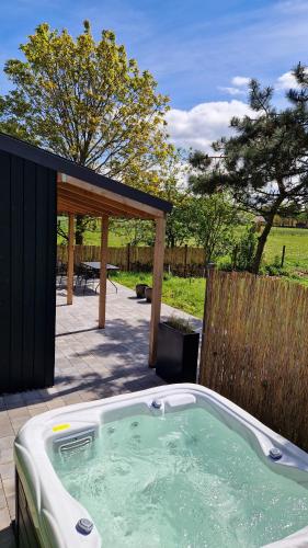a jacuzzi tub in a backyard with a picnic shelter at Chalet de Scherpenweide in Leur