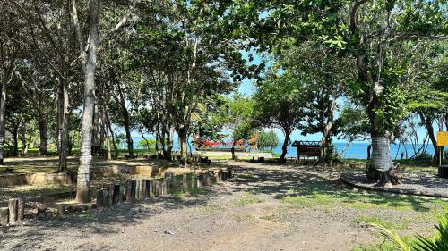 a park with trees and a bench next to the water at G Beach Hotel in Grajagan