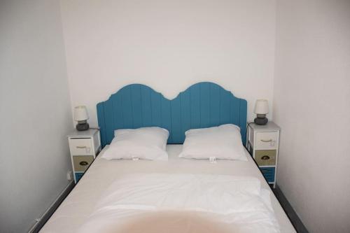 un lit avec une tête de lit bleue et 2 tables de chevet dans l'établissement Les maisons de L'Océan, aux Mathes