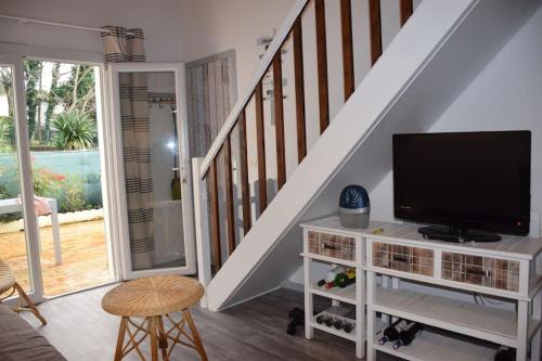 un salon avec une télévision et un escalier dans l'établissement Les maisons de L'Océan, aux Mathes