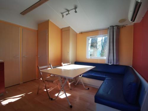 een woonkamer met een tafel en een blauwe bank bij F022 Mobil Home 3chambres 6personnes tout confort in La Boissière-de-Montaigu