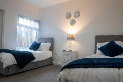 sypialnia z 2 łóżkami i lampką na ścianie w obiekcie Central 2-Bedroom Apartment with Wifi in Kettering by HP Accommodation w mieście Kettering