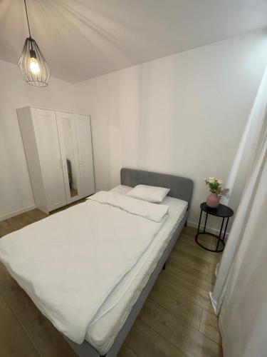 a white bed in a small room with a lamp at Marcelin Business & Family in Poznań