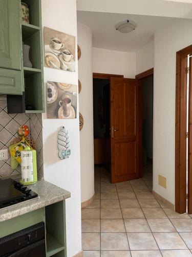 uma cozinha com armários verdes e piso em azulejo em Casa Castelsardo con giardino em Castelsardo