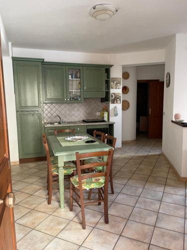 uma cozinha com armários verdes e uma mesa e cadeiras em Casa Castelsardo con giardino em Castelsardo