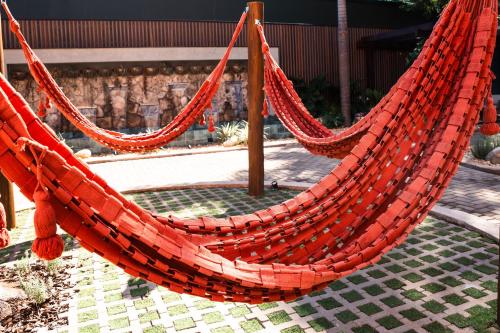 two red hammocks are hanging in a garden at Foz Plaza Hotel in Foz do Iguaçu