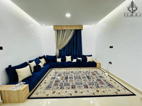 - un salon avec un canapé bleu et un tapis dans l'établissement Agharina furnished apartments, à Nouakchott