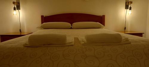 a bedroom with a bed with two pillows and two lamps at Murta's Home in Cadaval
