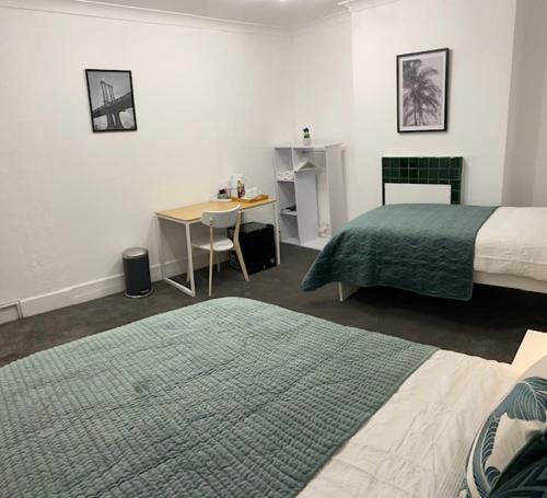a room with two beds and a table and a desk at GUEST ROOMS in CAMDEN TOWN in London
